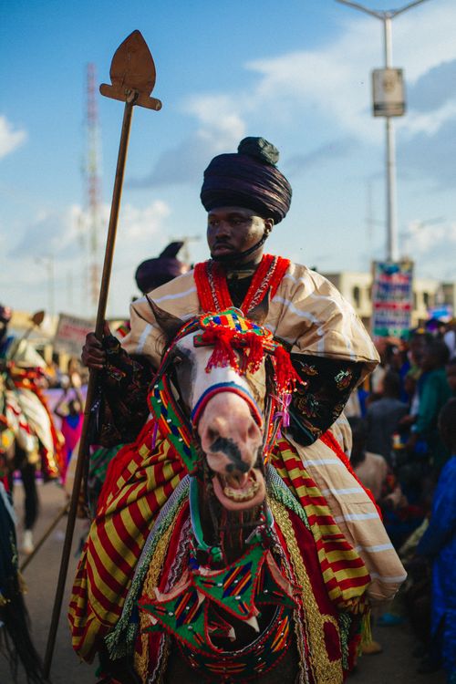 Free Vibrant festival scene with man in traditional attire riding decorated horse. Stock Photo