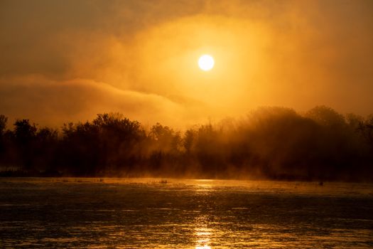A serene sunrise over a misty lake with fog and reflections in Tell, Wisconsin, USA.