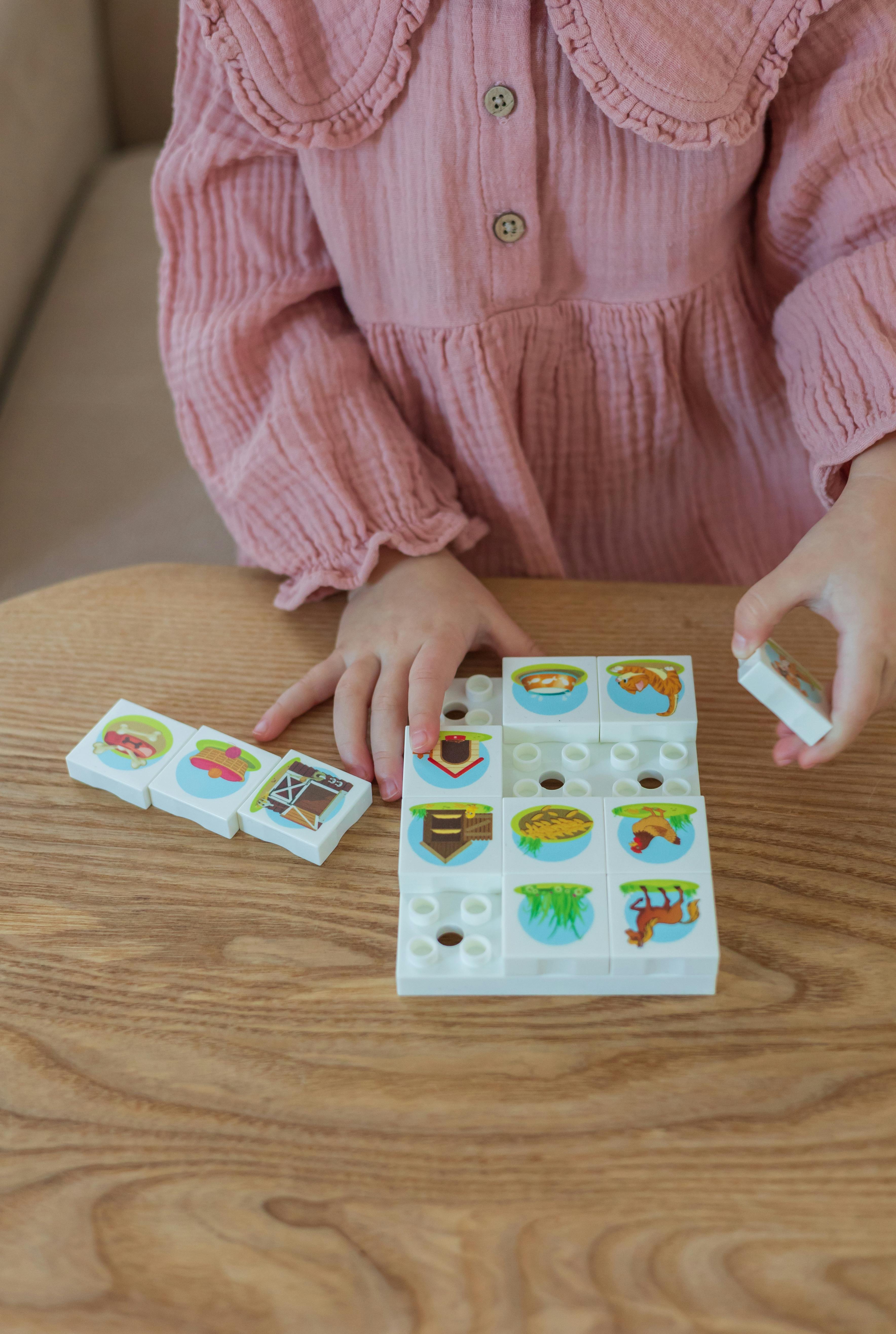 Young child engaging with a colorful educational toy on a wooden table indoors.