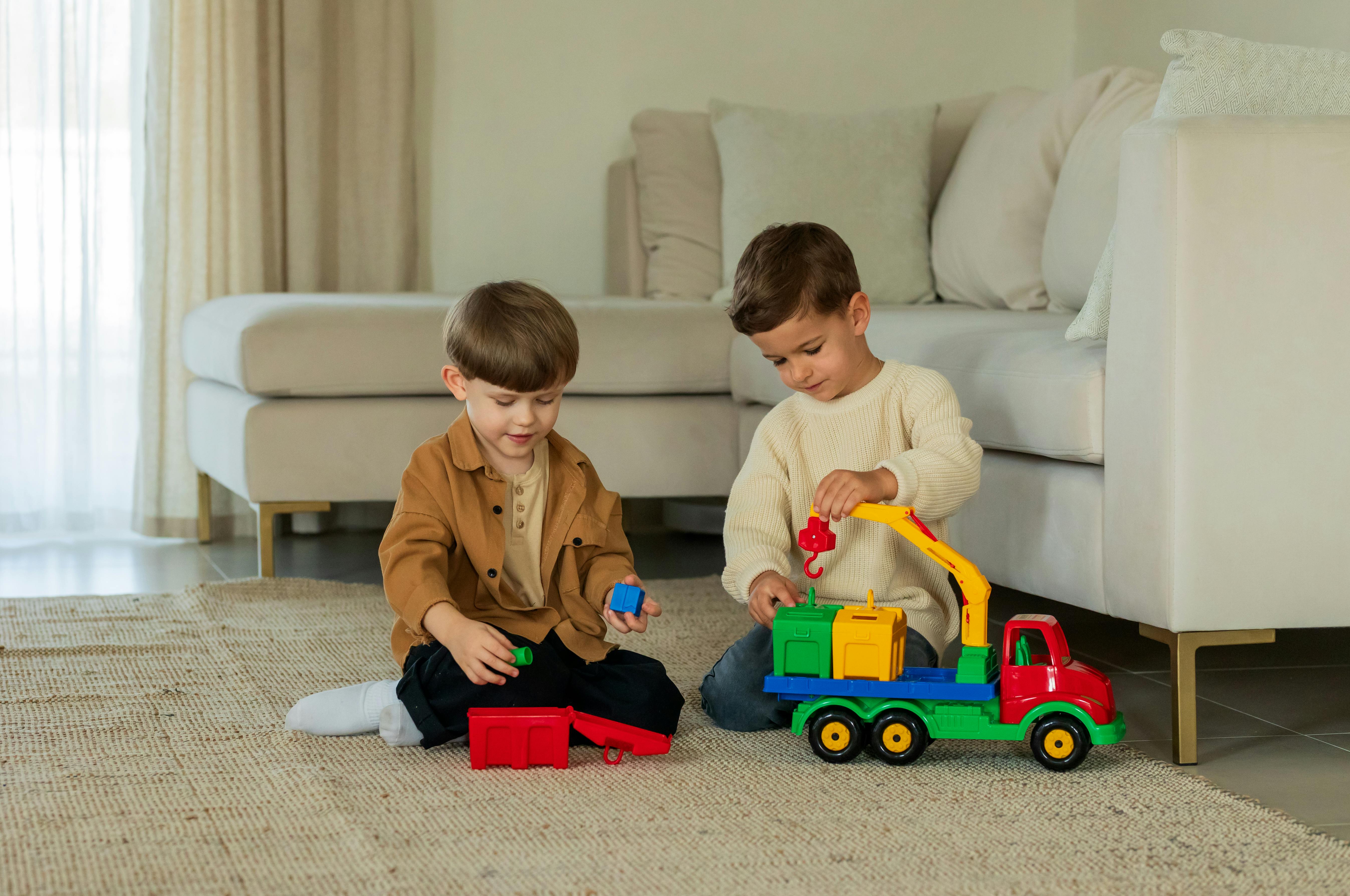 Two young boys having fun with colorful toy trucks on a rug in a cozy living room.