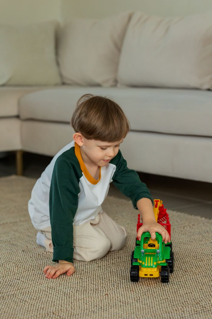Young boy playing with a colourful toy tractor indoors