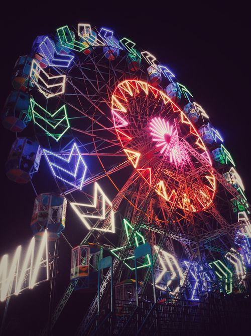Free Dazzling neon-lit ferris wheel captured at night, displaying vibrant colors and lights. Stock Photo