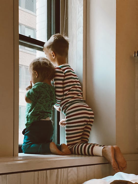 Free Two Boys Looking Outside Window Stock Photo