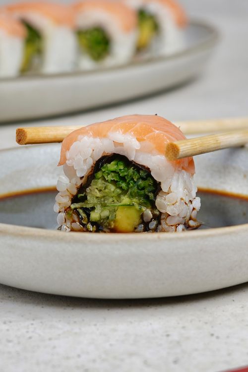 Free Delicious close-up of a sushi roll with salmon, highlighted by chopsticks for an authentic touch. Stock Photo
