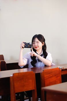 Young woman in classroom using a vintage camera for photography.