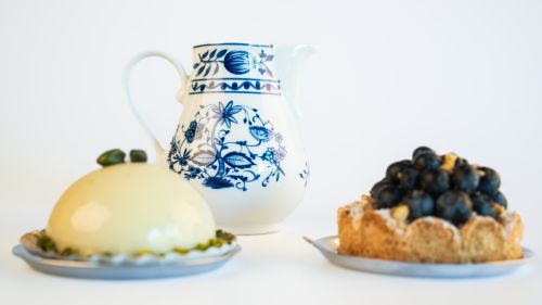 Free A floral porcelain pitcher surrounded by delicious cakes and pastries on a white background. Stock Photo