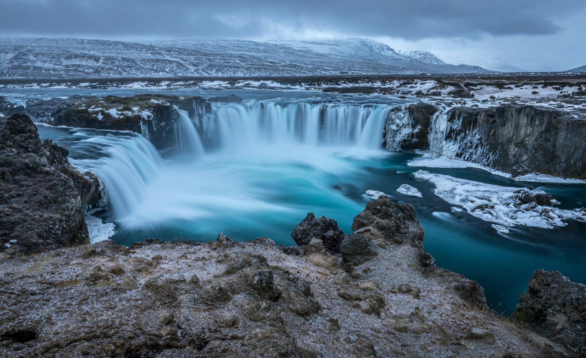 Majestic Godafoss waterfall captured in winter, showcasing icy landscape and stunning blue waters.