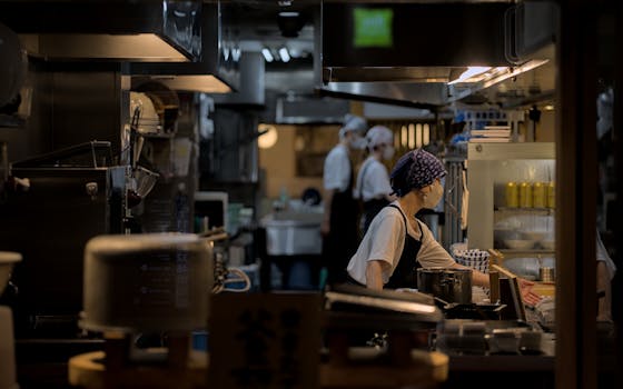 A bustling restaurant kitchen in Kyoto, Japan at night, showcasing staff in action.