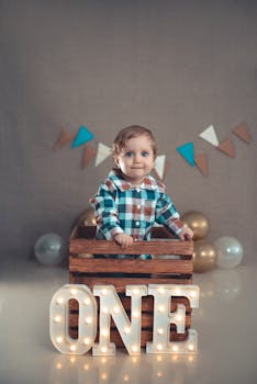 Baby celebrating first birthday in crate with ONE sign and balloons.