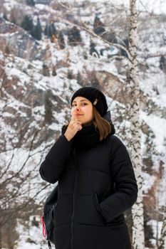冰雪覆盖的树木间，一位时尚女子身着冬装