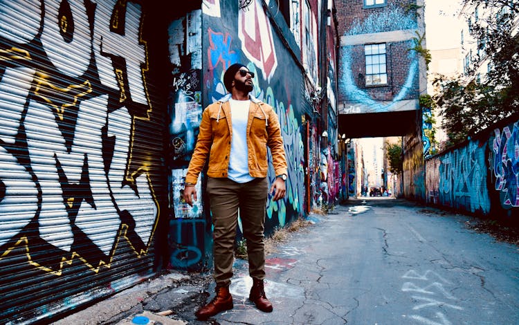 Man Standing Beside Building With Murals