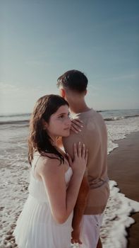 A couple embracing on a sunny beach, capturing a moment of romance and tranquility by the ocean.