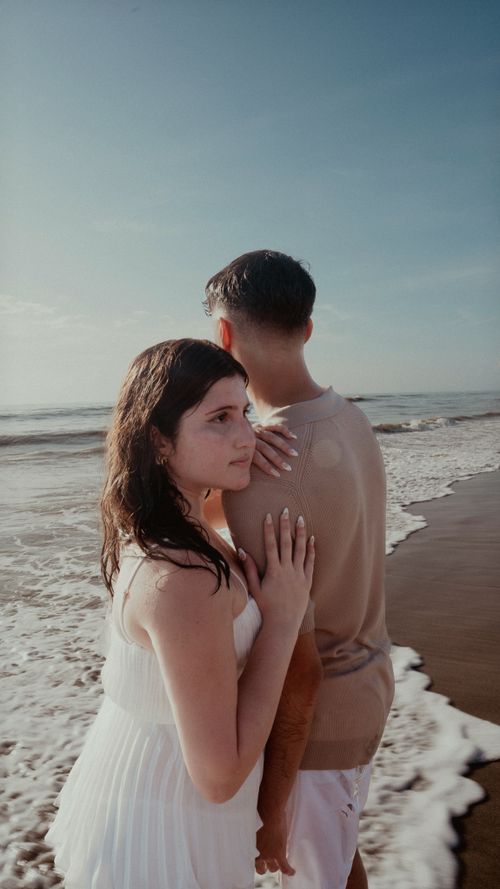 Free A couple embracing on a sunny beach, capturing a moment of romance and tranquility by the ocean. Stock Photo