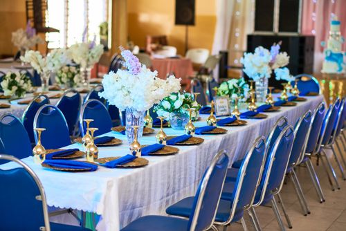 Free Chic wedding reception setup featuring blue chairs, floral arrangements, and gold accents. Stock Photo