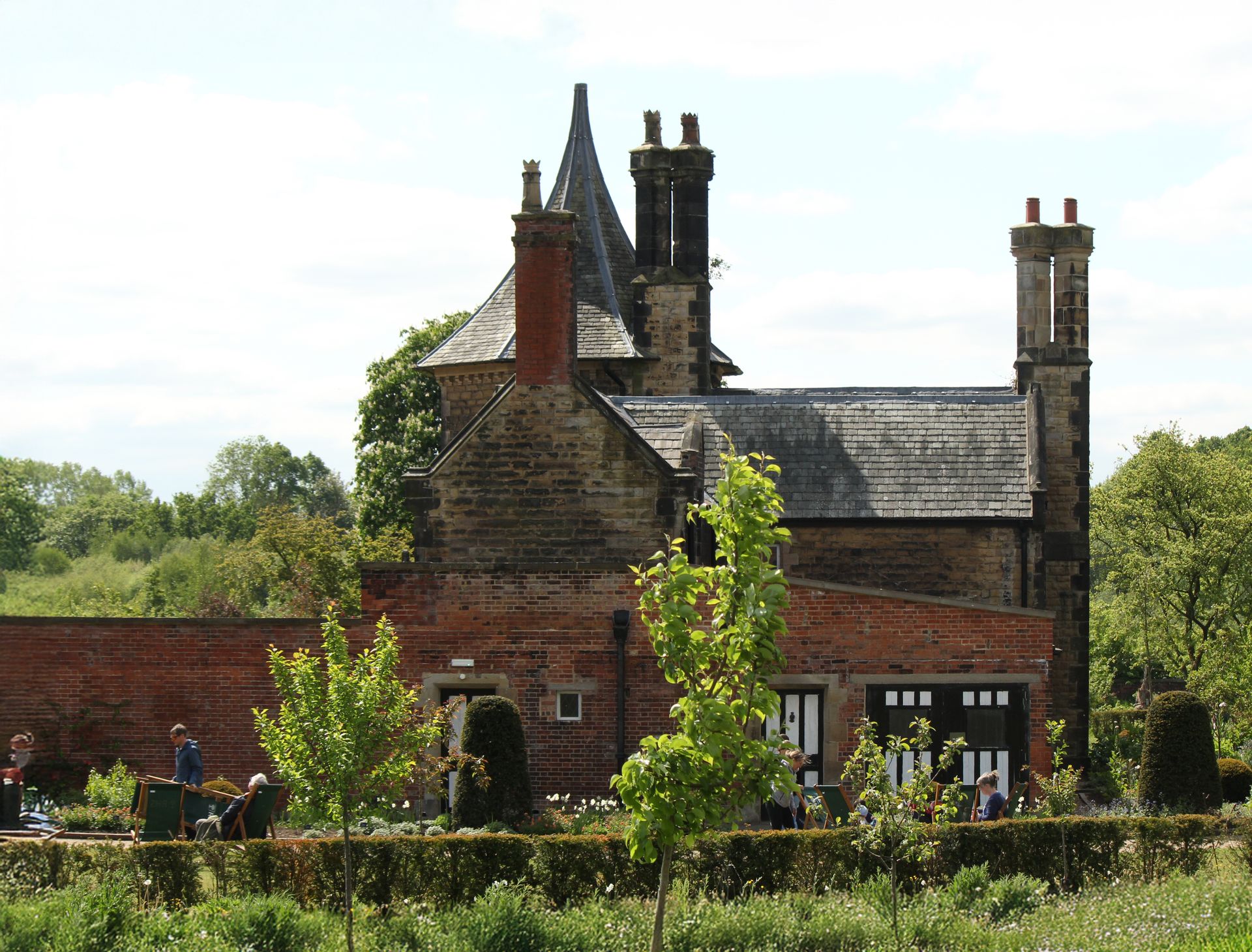 A picturesque historic house with a lush garden in the English countryside.
