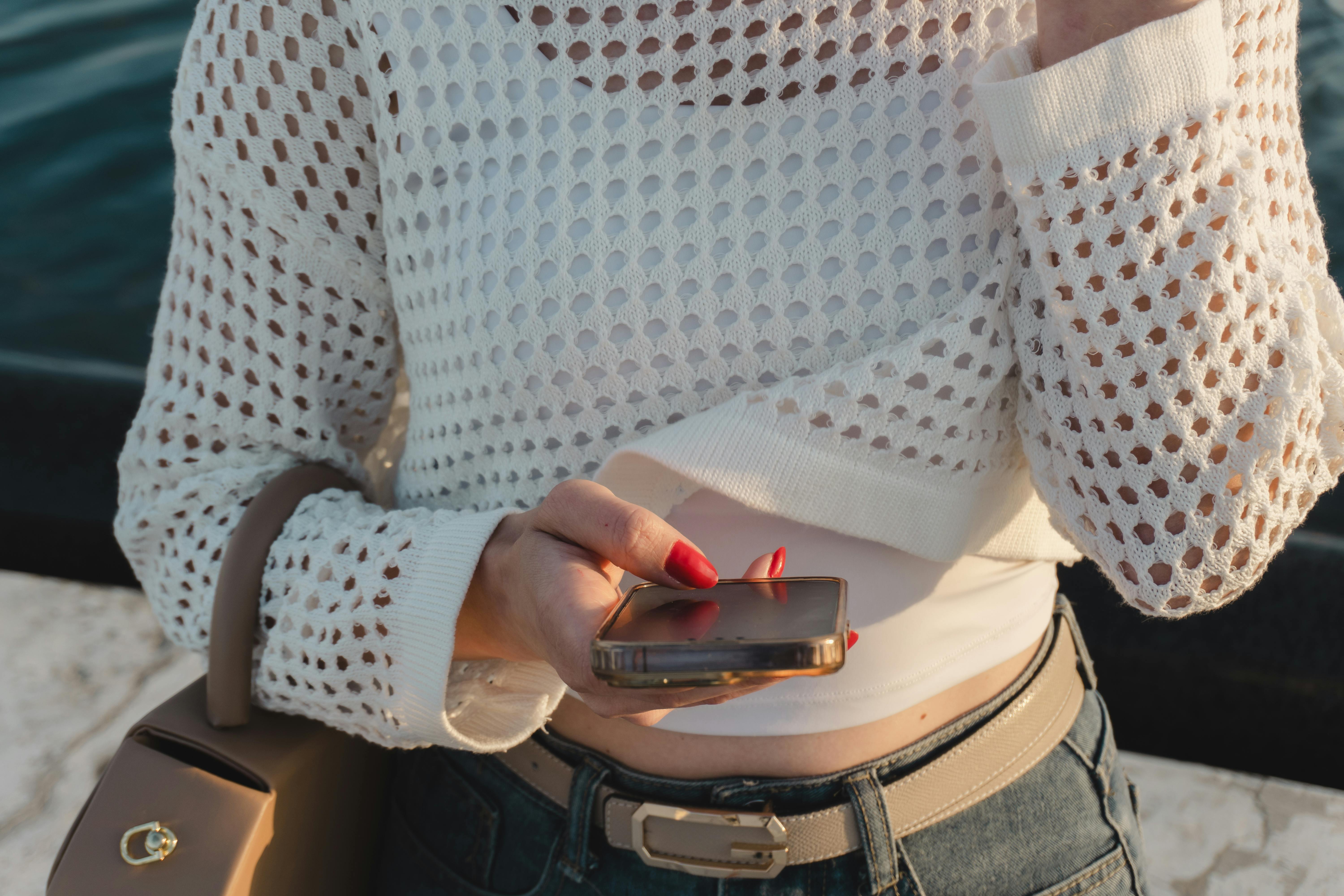 Gratis Wanita berpakaian kasual memeriksa telepon pintar di tepi sungai, bergaya dan modern. Foto Stok