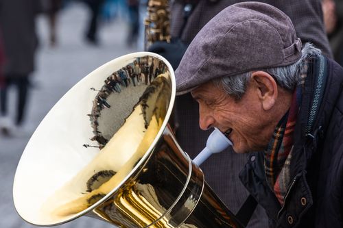 Free An elderly musician plays a tuba on the streets of Prague, capturing a lively street scene. Stock Photo