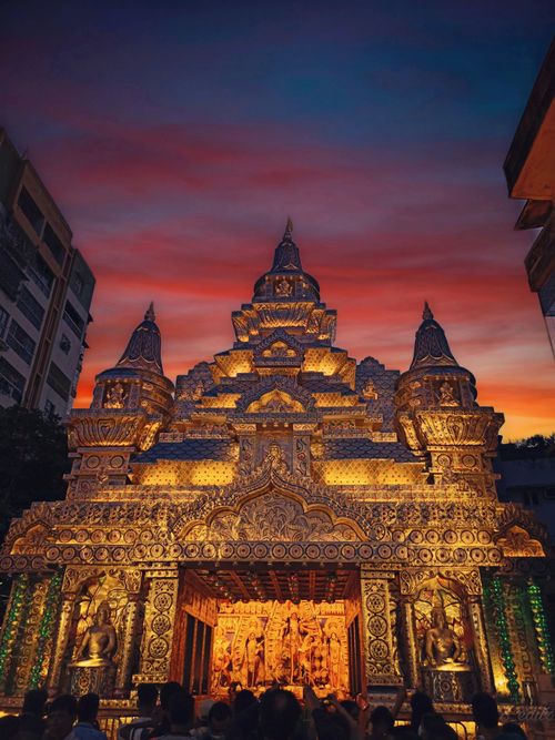Free Stunning Durga Puja pandal with intricate designs under a vivid sunset sky in Kolkata, India. Stock Photo