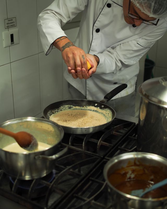 Chef finishing a sauce with citrus in a restaurant kitchen