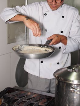 Chef seasoned dish in modern kitchen, showcasing culinary skills and techniques.