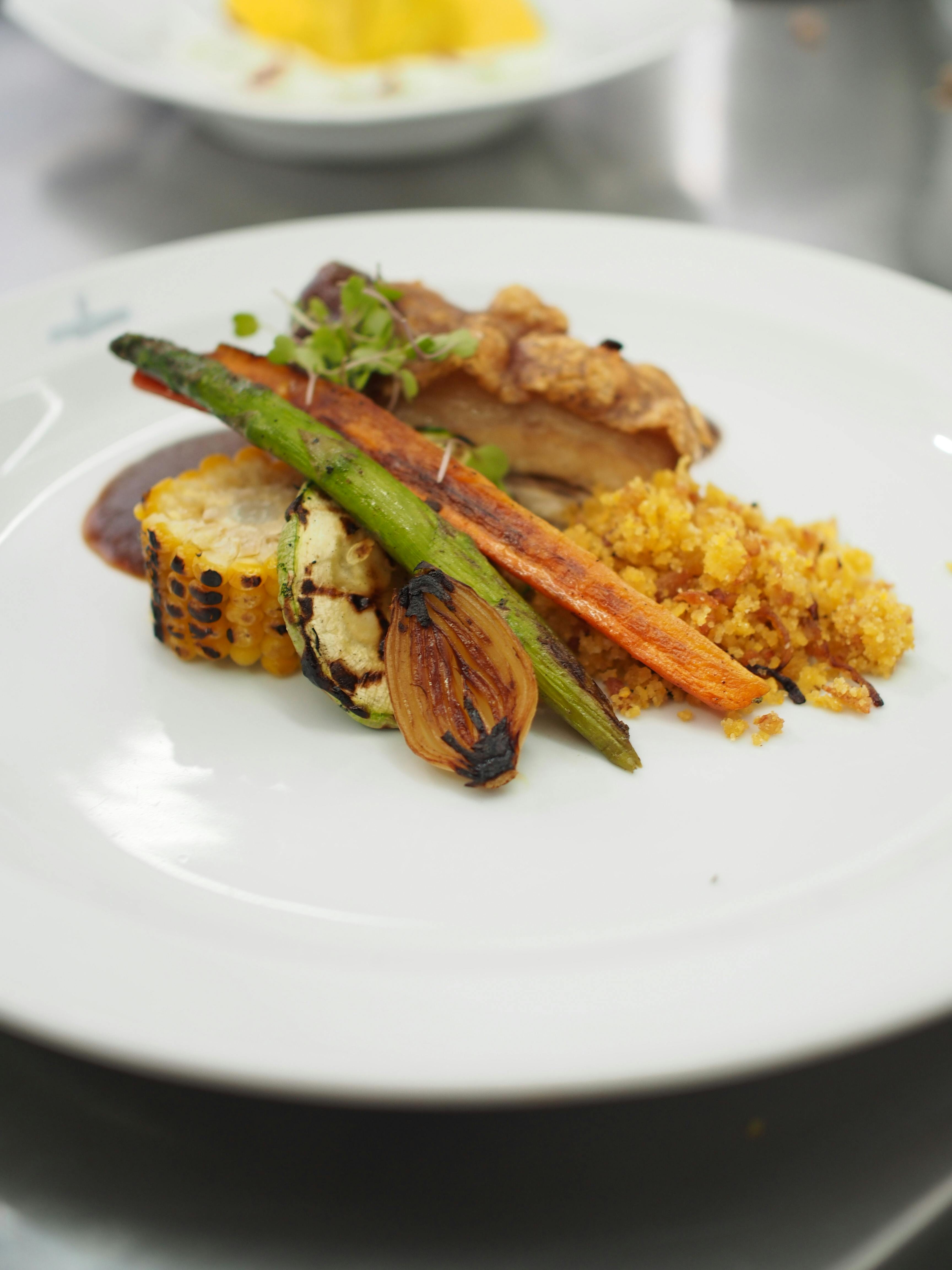 A generous plate of pulled Cajun pork shoulder with charred trinity vegetables, showing the deep mahogany crust and tender, shredded interior alongside caramelized onions, peppers, and celery