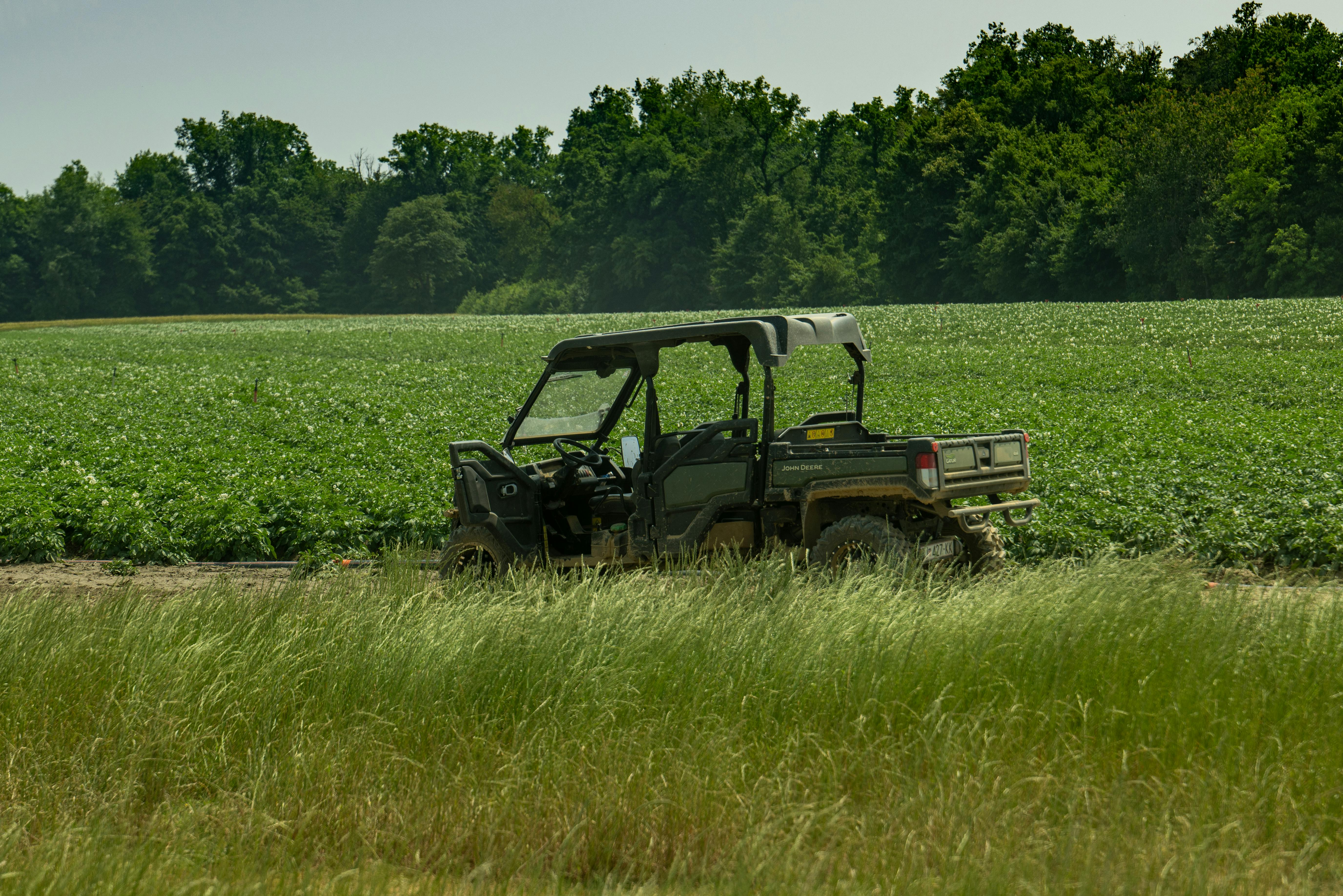 A utility vehicle rests in a verdant field in Garešnica, Croatia, surrounded by lush greenery.