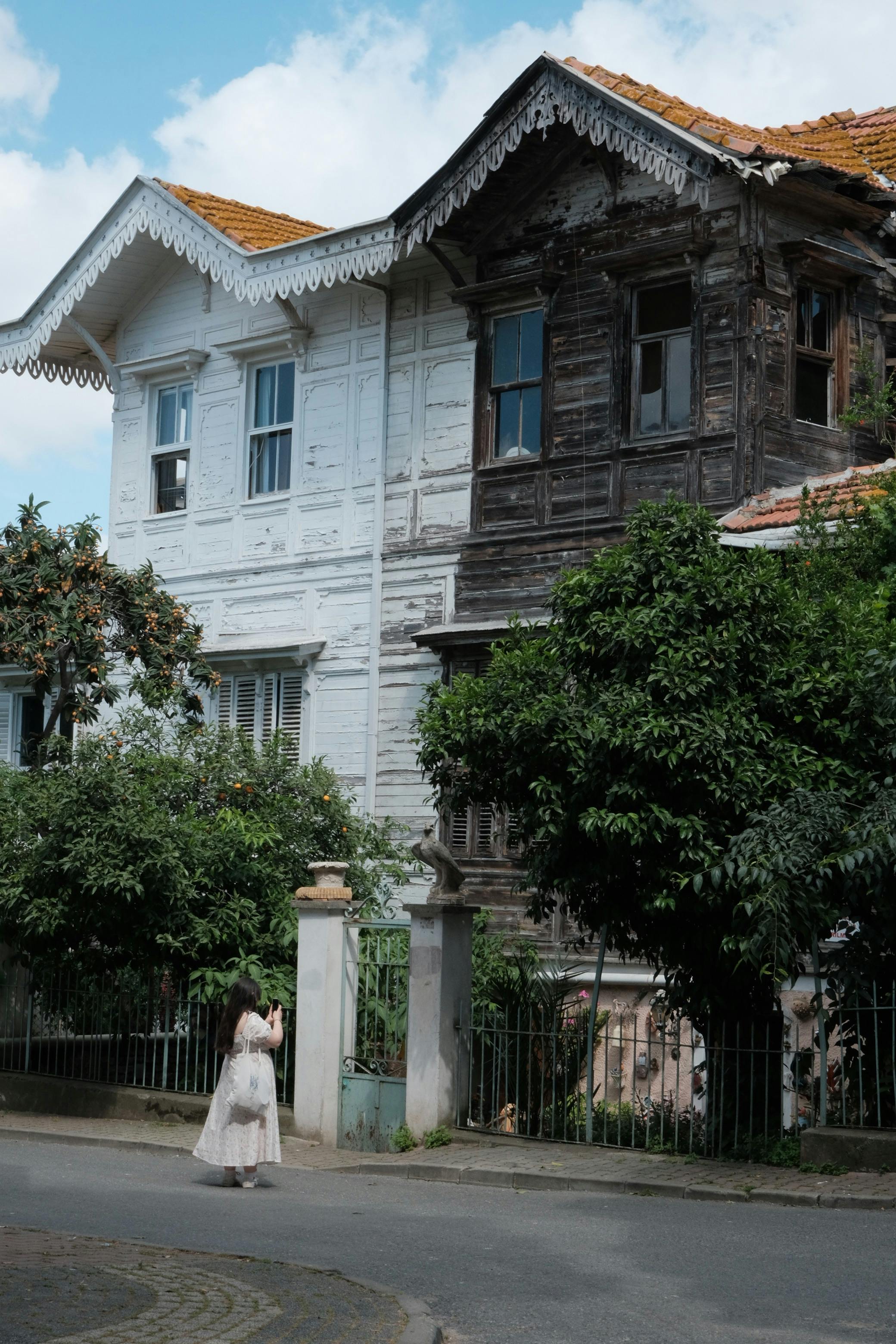 A historic wooden house with a passerby on Büyükada, İstanbul, capturing a nostalgic scene.