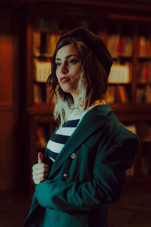 Free Stylish woman in a beret poses elegantly in a vintage library setting, exuding French elegance. Stock Photo