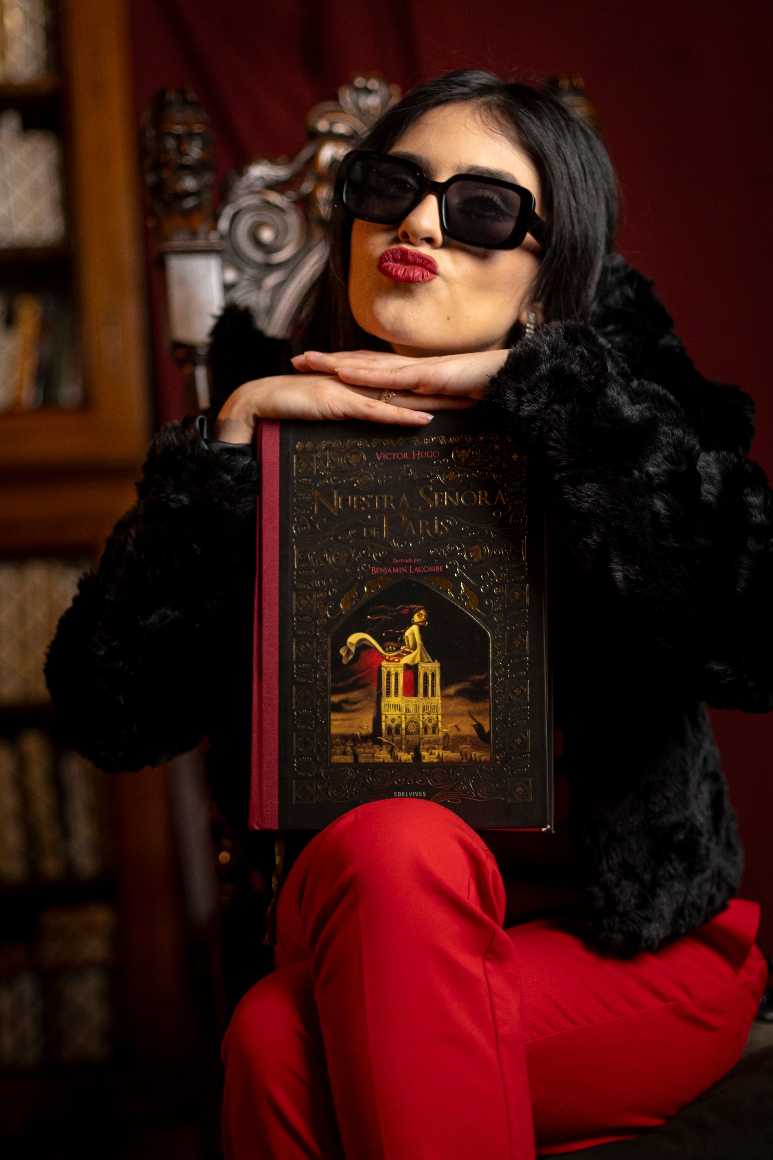 A fashionable woman poses with a book in a classic Buenos Aires library, exuding elegance and mystery.