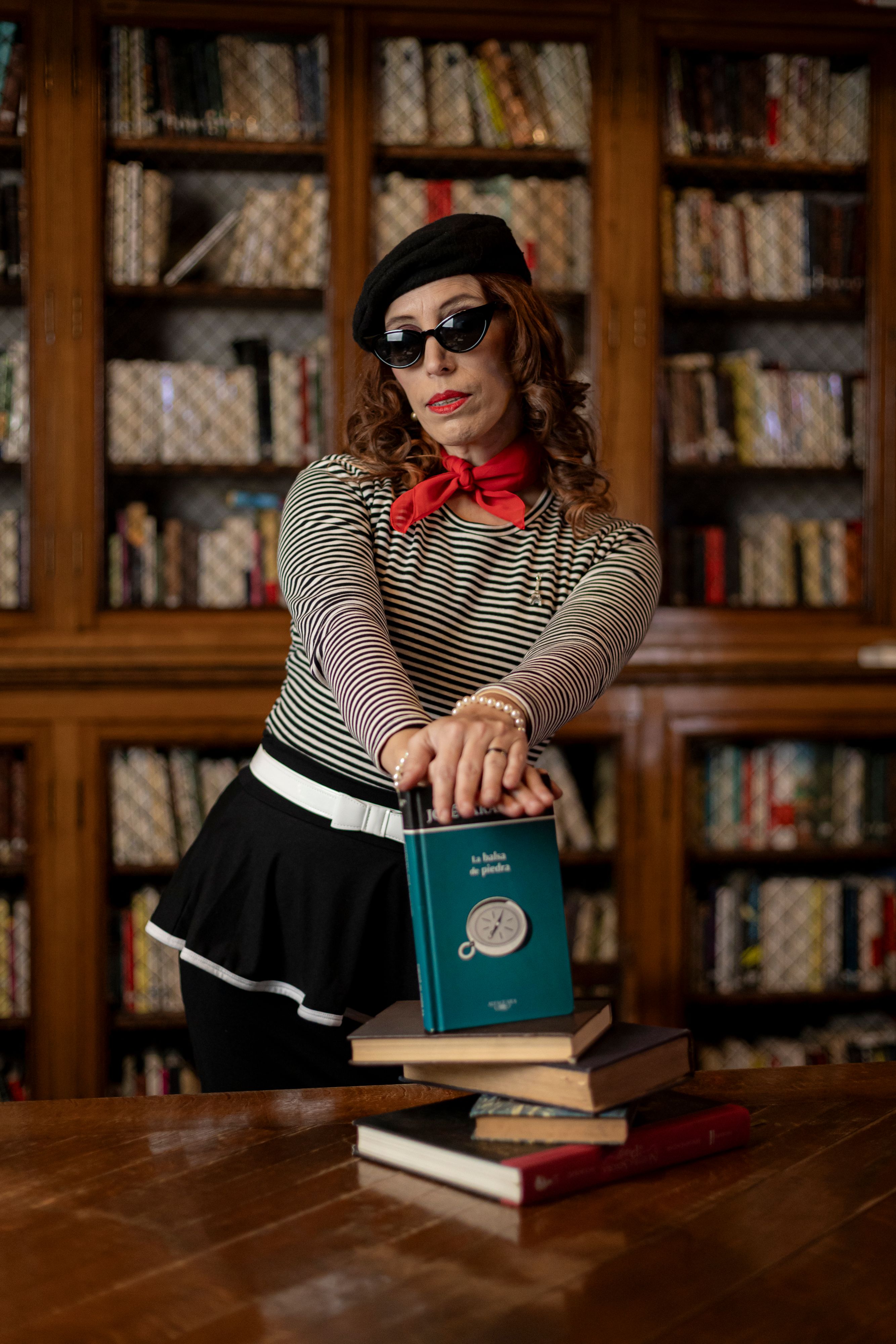 Woman in classic French outfit posing with books in a Buenos Aires library, exuding a chic and literary vibe.