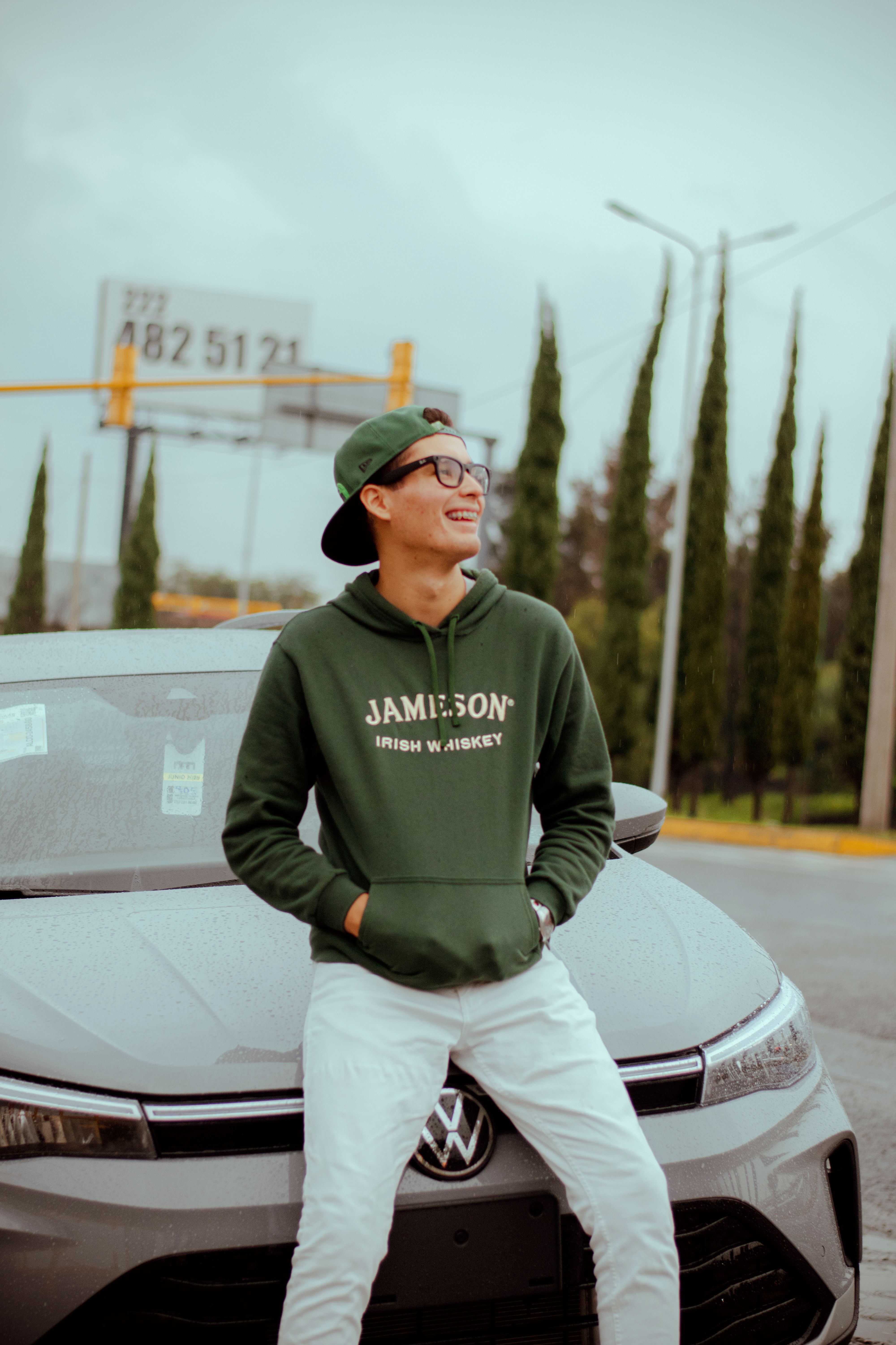 Casually dressed young adult leaning on a car outdoors, exuding a relaxed urban vibe.