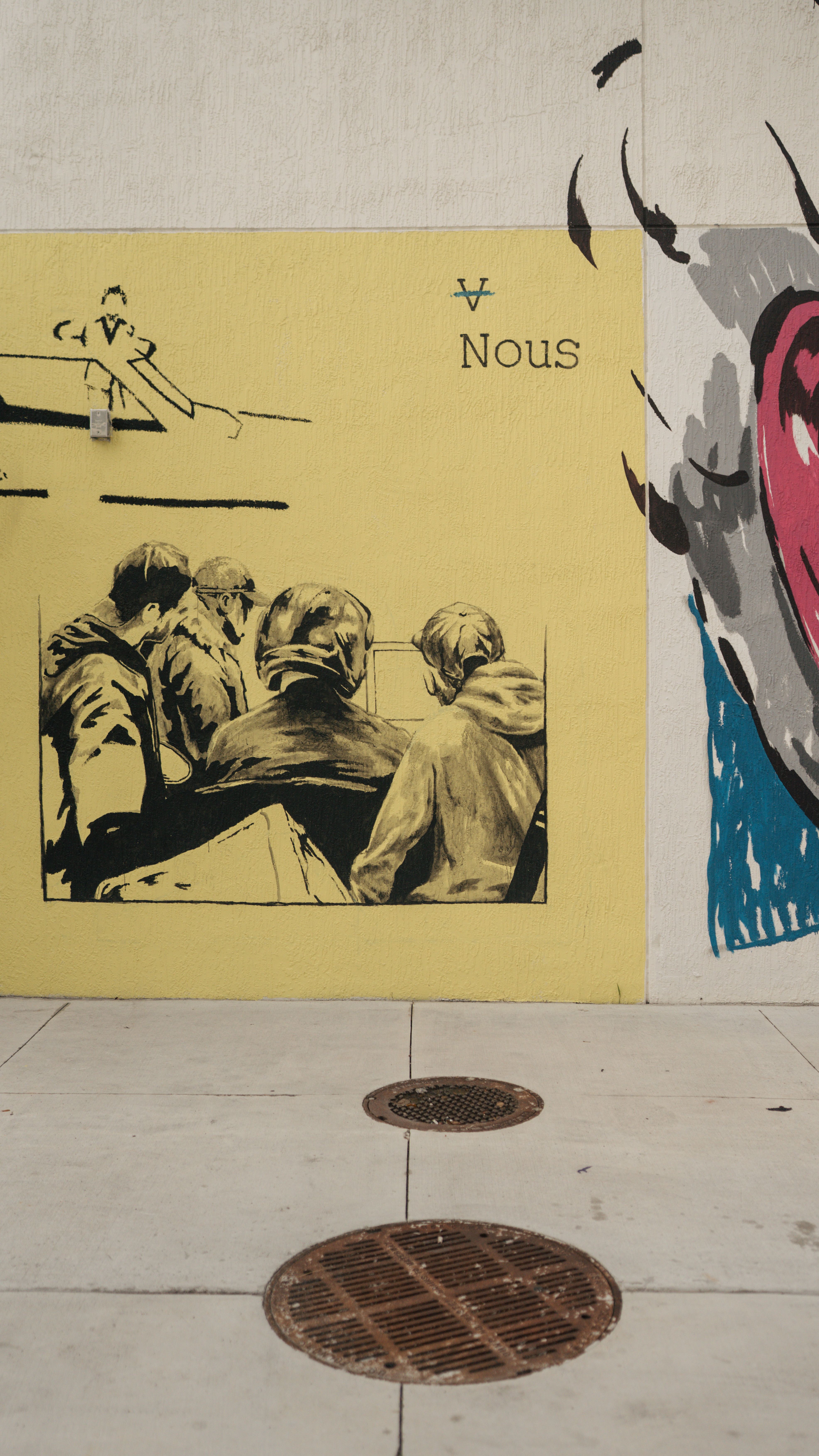Street art mural featuring a group of people on a yellow background with the word 'Nous.'