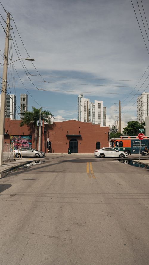 Free City street with cars, a brown building, and skyscrapers in the background. Ideal urban backdrop. Stock Photo