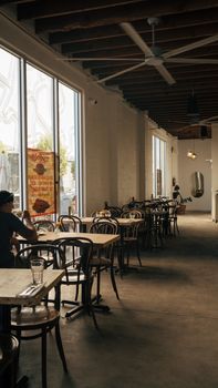 Warm and inviting cafe interior with large windows, wooden furniture, and a relaxed atmosphere.
