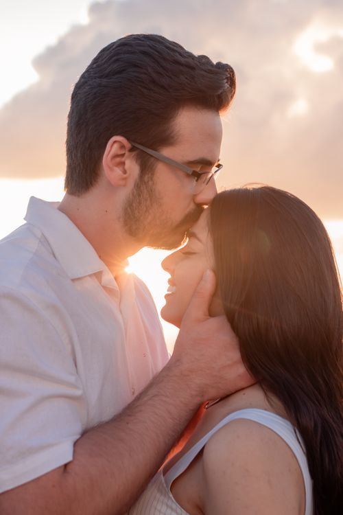 Free Couple sharing a tender moment with a sunset backdrop, showcasing love and intimacy. Stock Photo