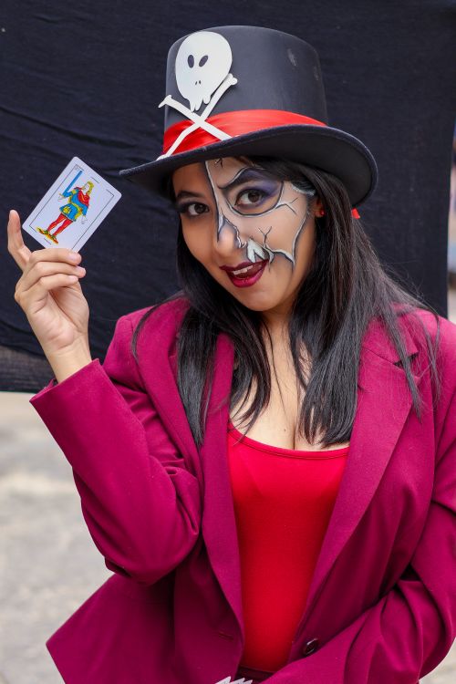 Free Smiling woman in costume with face paint holds a tarot card, exuding mystery. Stock Photo