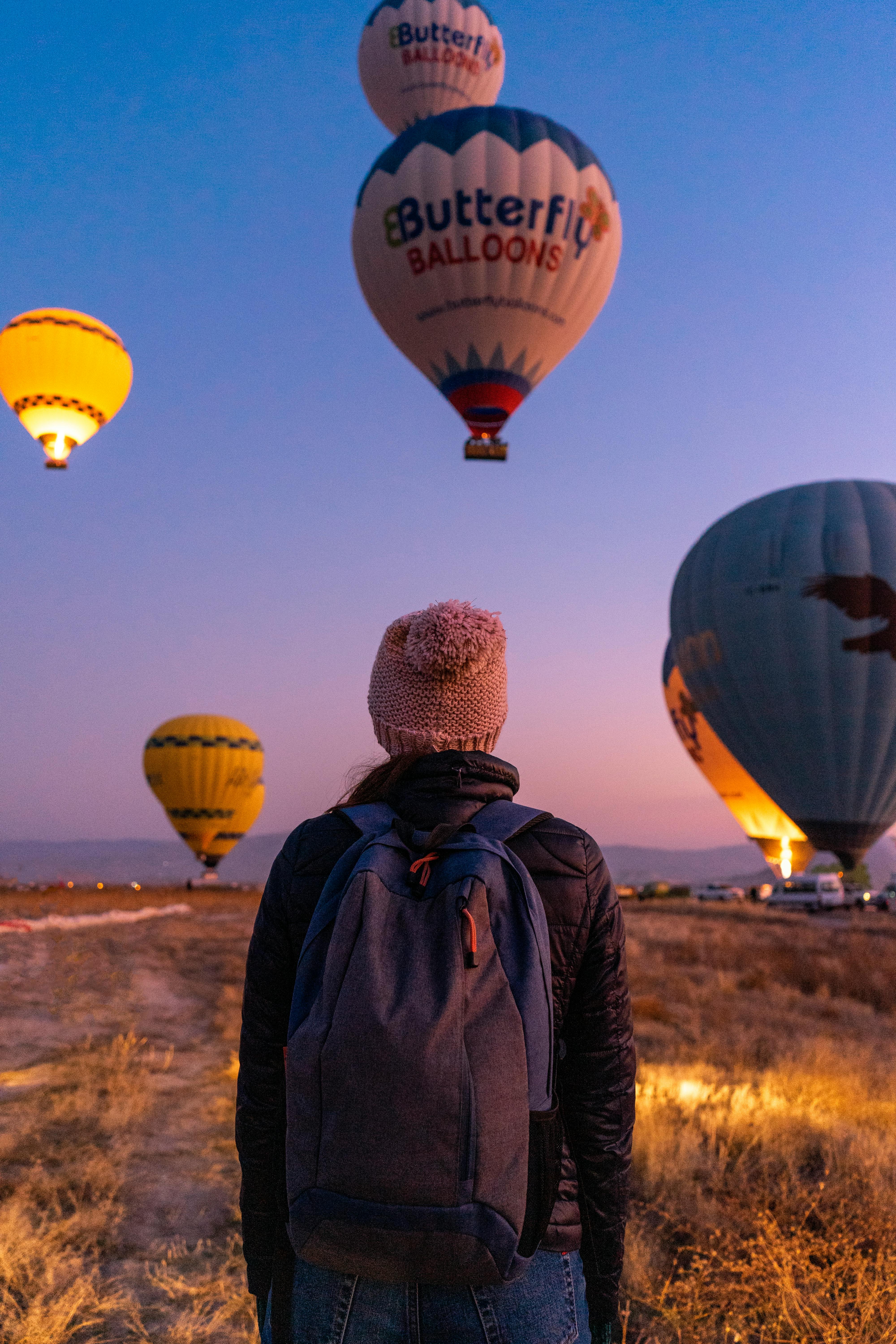 back view of a person carrying a backpack while watching the hot air balloons