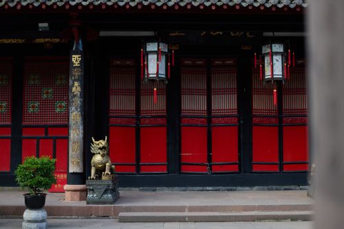Free A traditional Chinese temple entrance with red lanterns and a guardian statue. Stock Photo