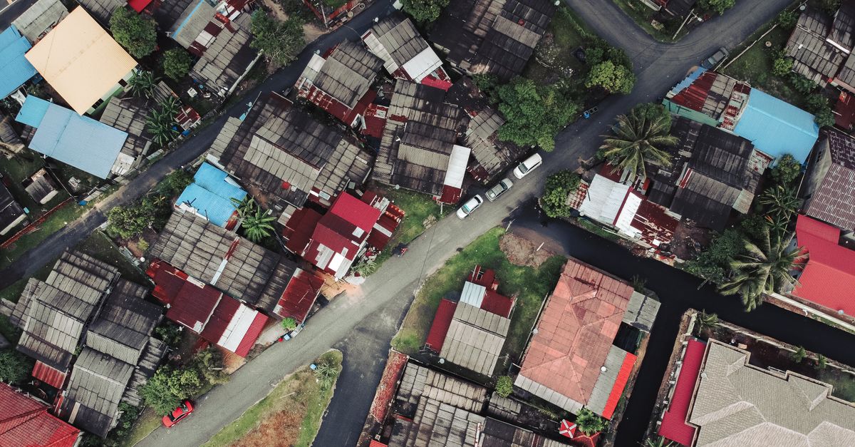Vibrant aerial shot of urban rooftops and streets in a tropical area with lush greenery.