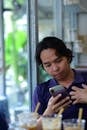 Man Engaged with Smartphone in Cafe Setting