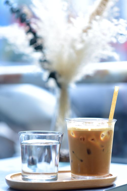 Free Iced coffee and water on a wooden tray, perfect for a cozy café experience. Stock Photo