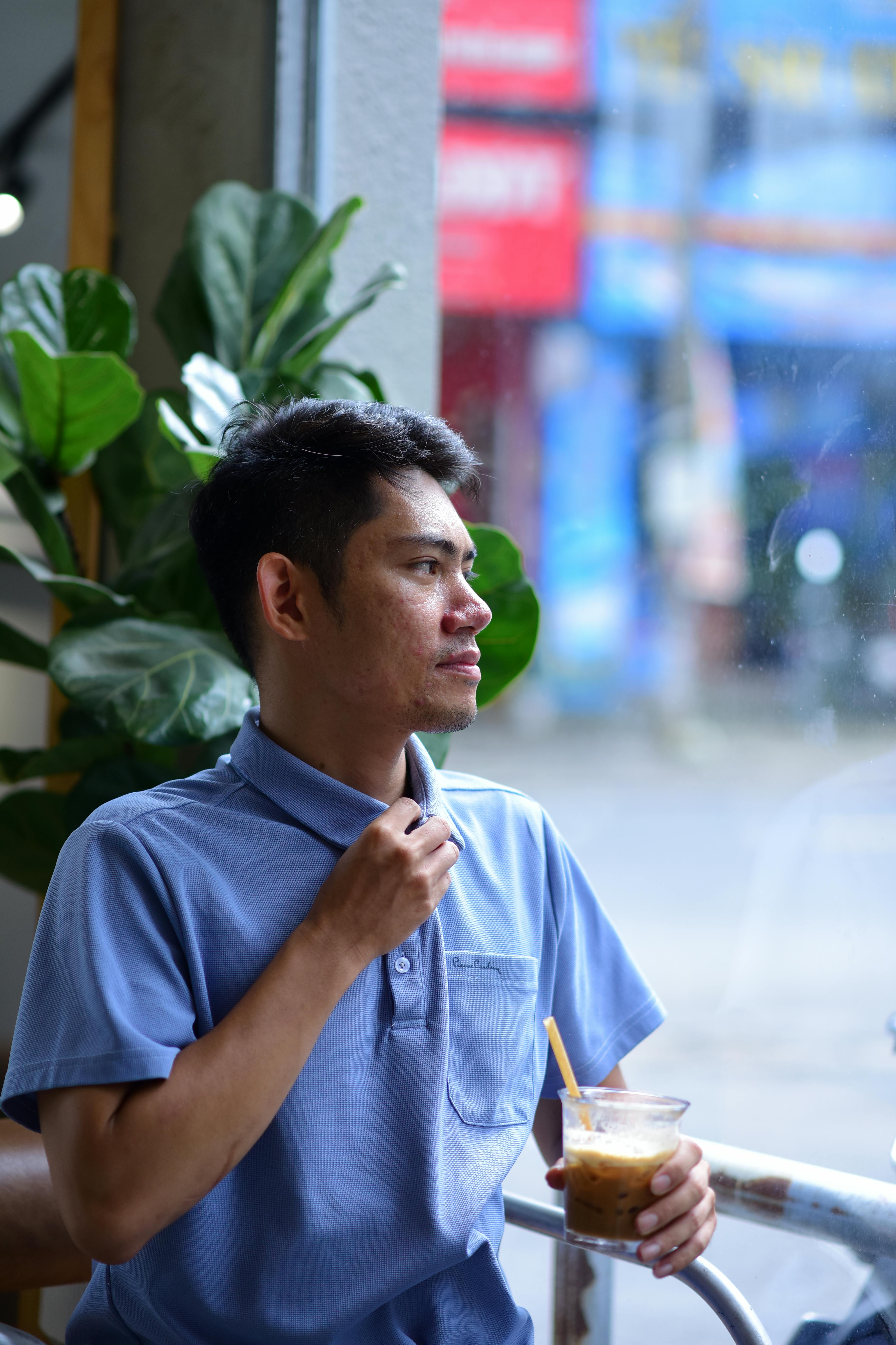 Free Alone in a café, a man enjoys his iced coffee, gazing thoughtfully out the window. Stock Photo