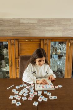 A young girl in a cozy room plays with alphabet blocks, enhancing learning and creativity.