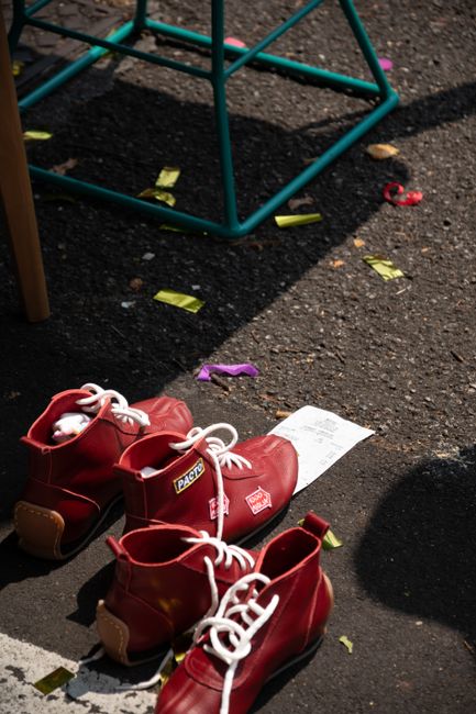 Red shoes on asphalt surrounded by confetti and outdoor elements, creating a vibrant street scene.