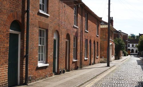 Free Sunlit view of traditional brick homes lining a cobblestone street in Norwich, UK. Stock Photo