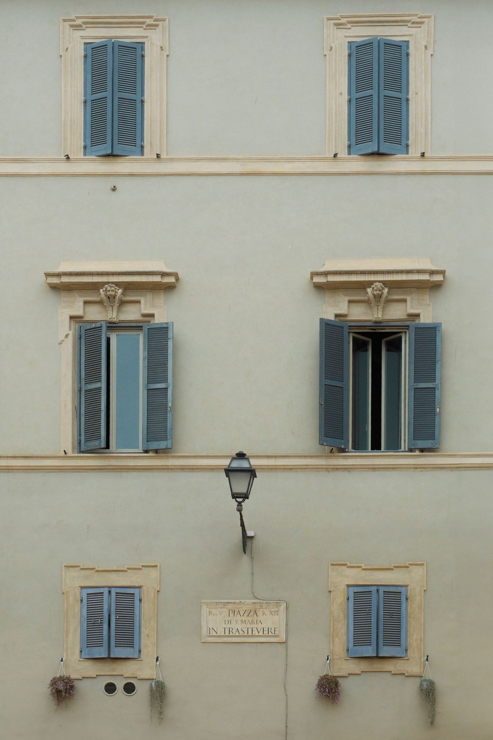 Classic European building facade featuring blue shutters and detailed stonework.