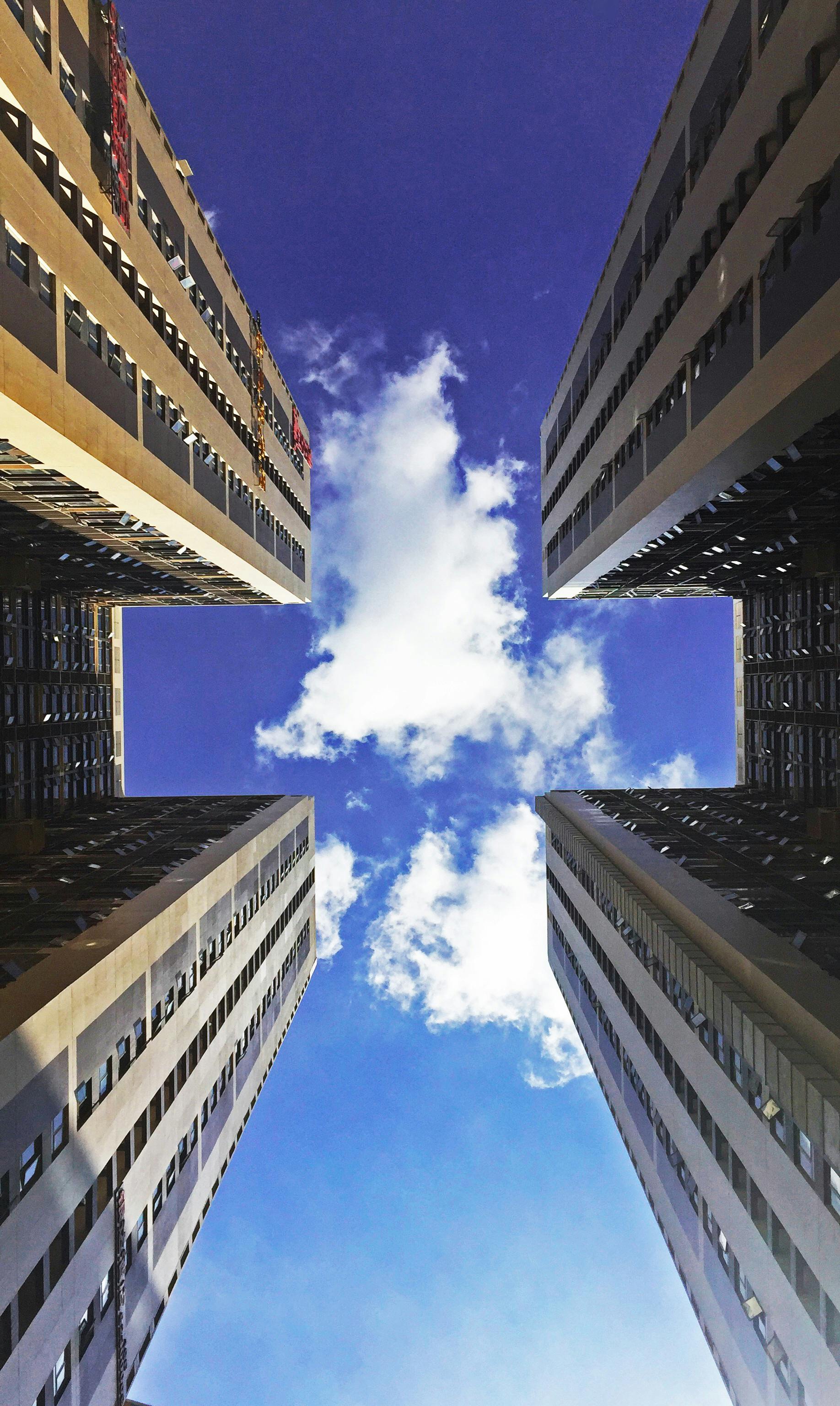 low angle view of skyscraper against cloudy sky