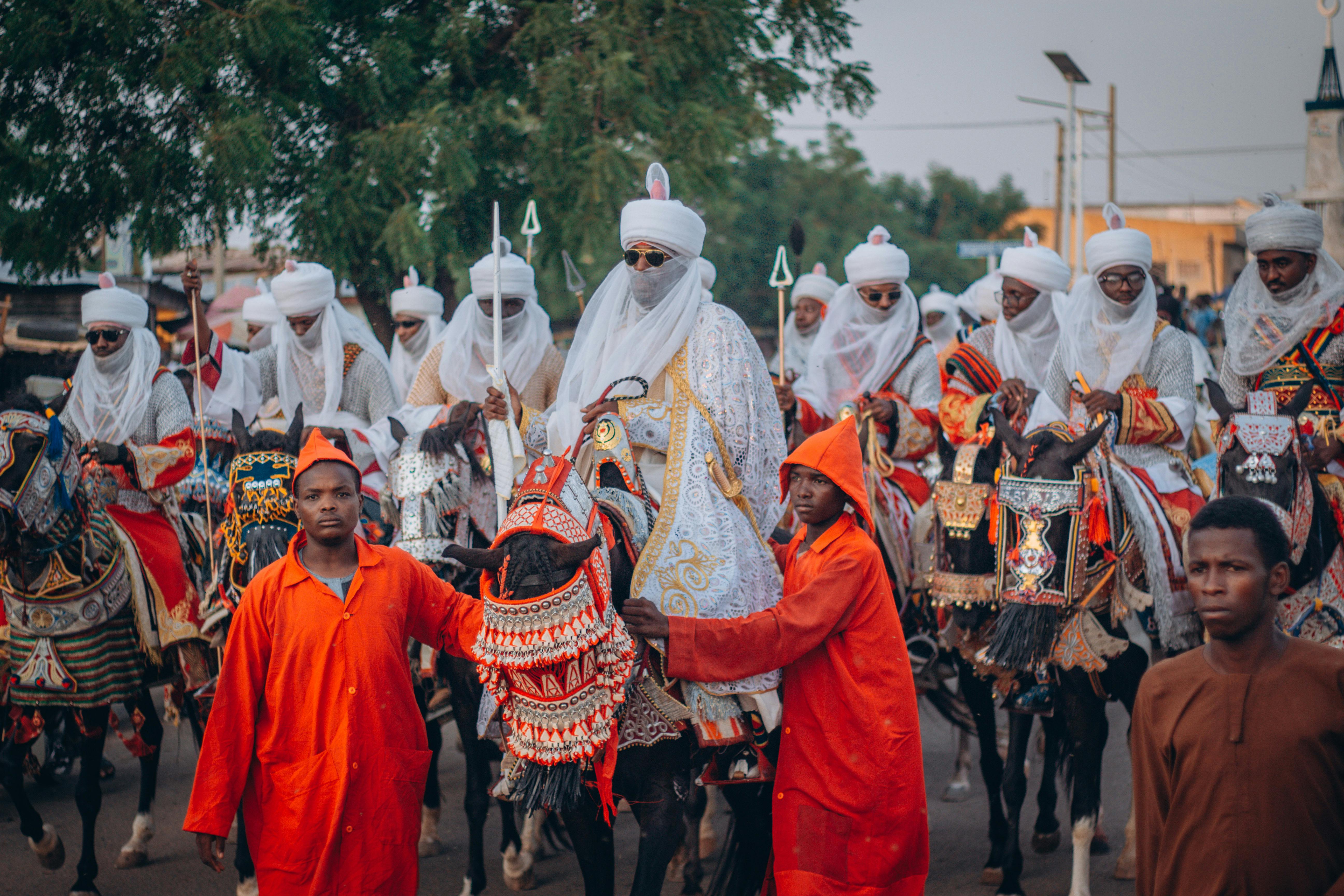 Vibrant cultural parade featuring adorned horses and Hausa riders during a traditional Nigerian festival.