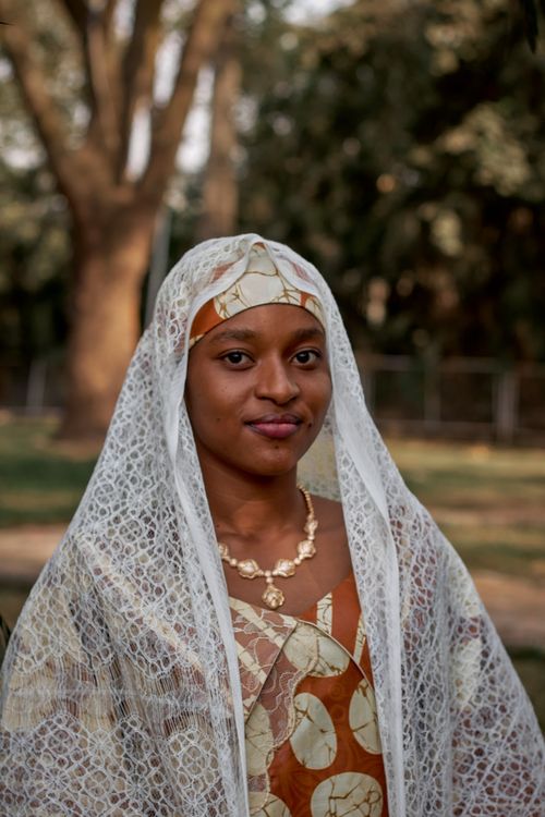 Free A young woman wearing traditional African clothing and lace veil in an outdoor setting. Stock Photo