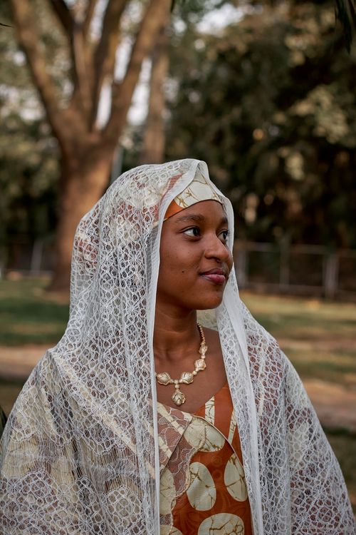 Free Portrait of a woman in traditional African attire with a lace veil, captured outdoors. Stock Photo
